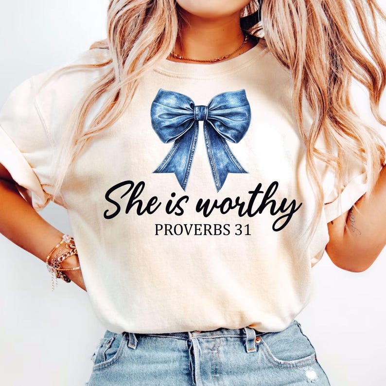 May include: A white t-shirt with a blue denim bow and the text "She is worthy Proverbs 31" printed on it.