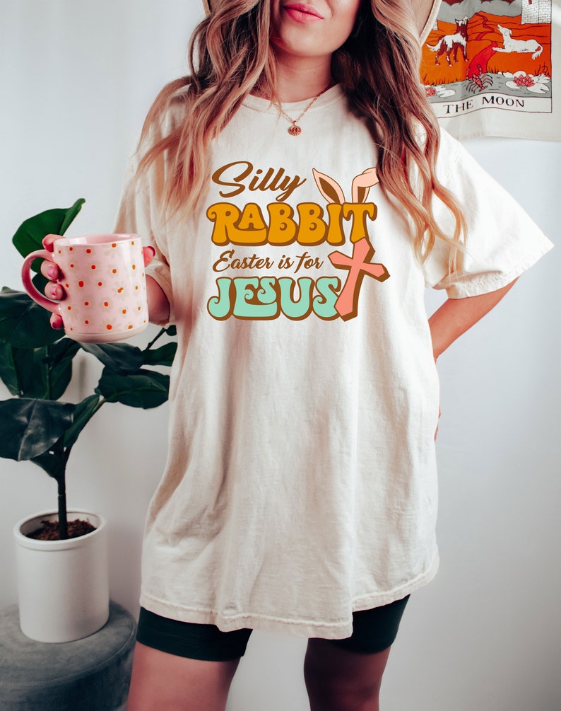 May include: A white t-shirt with a retro-style graphic that says "Silly Rabbit Easter is for Jesus" with a bunny ear and cross design.
