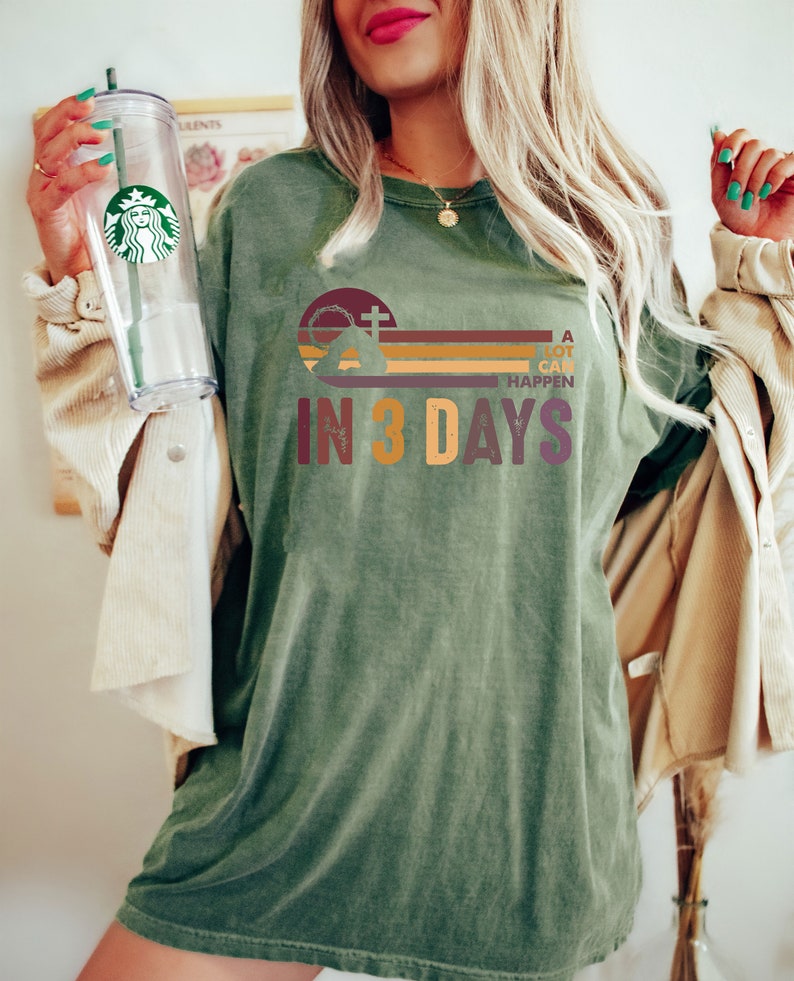 Może przedstawiać: Zielony T-shirt z retro grafiką przedstawiającą krzyż, koronę cierniową i tekst "A lot can happen in 3 days".