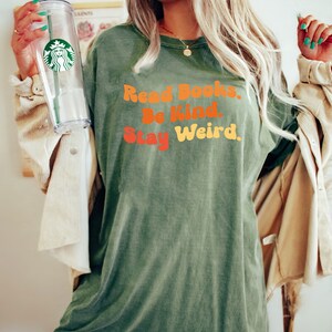 K&ouml;nnte beinhalten: Gr&uuml;nes T-Shirt mit dem Text "Read Books. Be Kind. Stay Weird." in einer Retro-Schrift.