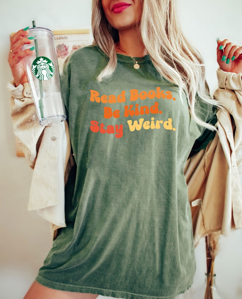 K&ouml;nnte beinhalten: Gr&uuml;nes T-Shirt mit dem Text "Read Books. Be Kind. Stay Weird." in einer Retro-Schrift.