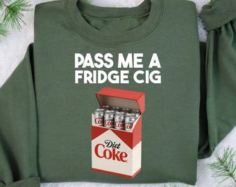 May include: An olive green sweatshirt with the text "PASS ME A FRIDGE CIG" in white. Below the text is a graphic of a Diet Coke box with several Diet Coke cans inside.