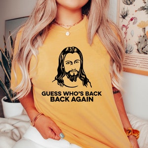 May include: A yellow t-shirt with a black and white image of Jesus and the text "Guess who's back back again".