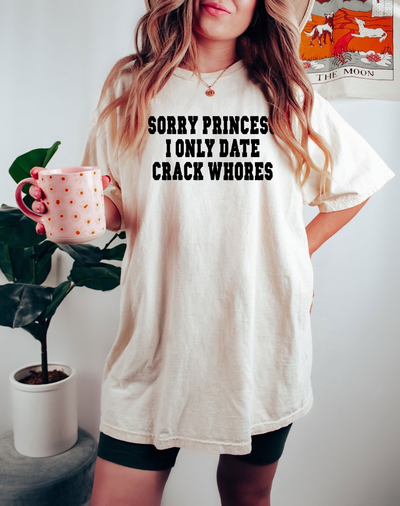May include: A white t-shirt with the text "Sorry Princes I Only Date Crack Whores" printed in black.