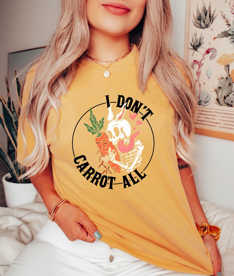 Może przedstawiać: Ż&oacute;łta koszulka z czarnym kołem graficznym przedstawiającym szkielet trzymający marchewkę i tekst "I Don't Carrot All".