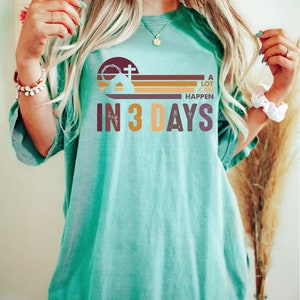 Może przedstawiać: Turkusowy t-shirt z nadrukiem graficznym przedstawiającym kości&oacute;ł z krzyżem, zach&oacute;d słońca i tekst "A lot can happen in 3 days".