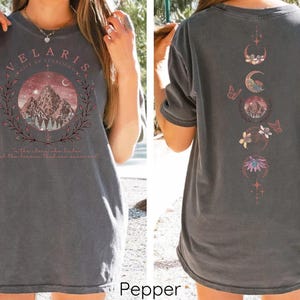 May include: A gray oversized t-shirt with a graphic print of a mountain range and the text "Velaris City of Starlight" on the front. The back of the shirt features a graphic print of a moon with stars, butterflies, and flowers.