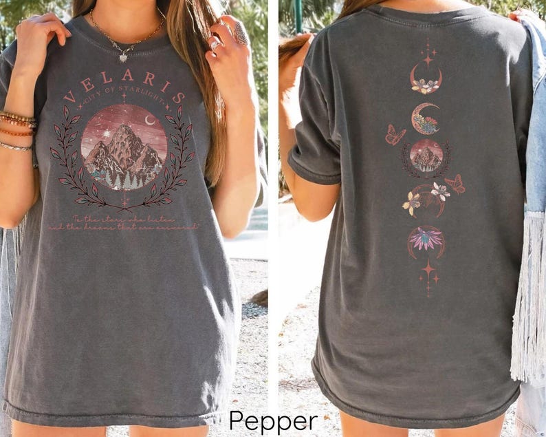 May include: A gray oversized t-shirt with a graphic print of a mountain range and the text "Velaris City of Starlight" on the front. The back of the shirt features a graphic print of a moon with stars, butterflies, and flowers.