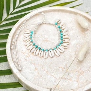 Può includere: Cavigliera con conchiglie bianche e perline turchesi su una superficie di marmo bianco.