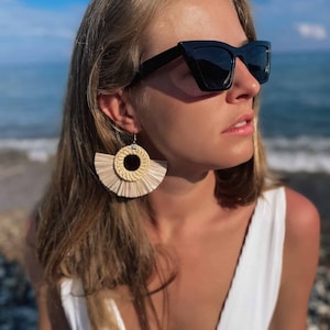 Może przedstawiać: Zestaw trzech ceramicznych wazonów o różnych wysokościach i kształtach. Najwyższy wazon jest jasnobeżowy, środkowy ciemnobrązowy, a najmniejszy nakrapiany biały. Każdy wazon ma unikalną, teksturowaną powierzchnię.