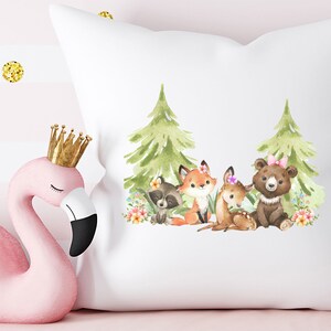 Peut inclure: Un oreiller blanc avec une illustration aquarelle d'un renard, d'un raton laveur, d'un cerf et d'un ours dans un d&eacute;cor de for&ecirc;t. Les animaux portent des fleurs et les arbres sont verts.