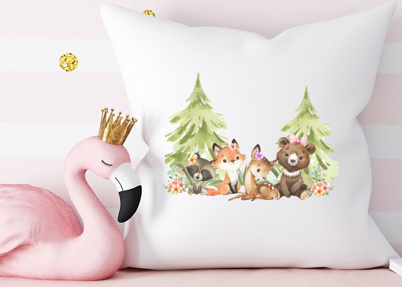 Peut inclure: Un oreiller blanc avec une illustration aquarelle d'un renard, d'un raton laveur, d'un cerf et d'un ours dans un d&eacute;cor de for&ecirc;t. Les animaux portent des fleurs et les arbres sont verts.