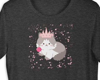Può includere: T-shirt grigio scuro con un gatto dei cartoni animati con una corona rosa e un lecca-lecca rosa a forma di cuore. Il gatto è bianco e grigio, con accenti rosa. Macchie rosa sullo sfondo.