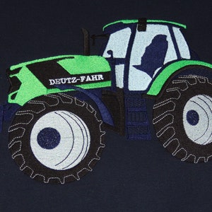 Peut inclure: Tracteur brodé vert et noir avec le texte "DEUTZ-FAHR" sur le côté. Le tracteur a un siège conducteur bleu et de grands pneus noirs.