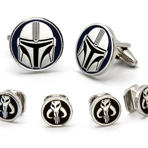 May include: A set of cufflinks and tie tacks featuring the Mandalorian's helmet and symbol. The cufflinks are silver with a blue background and the tie tacks are silver with a black background.