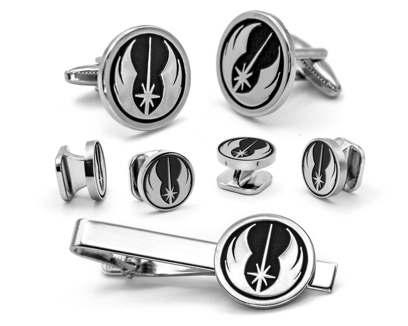 May include: A silver cufflink set featuring the Rebel Alliance symbol from Star Wars. The set includes two cufflinks, two shirt studs, and a tie bar.
