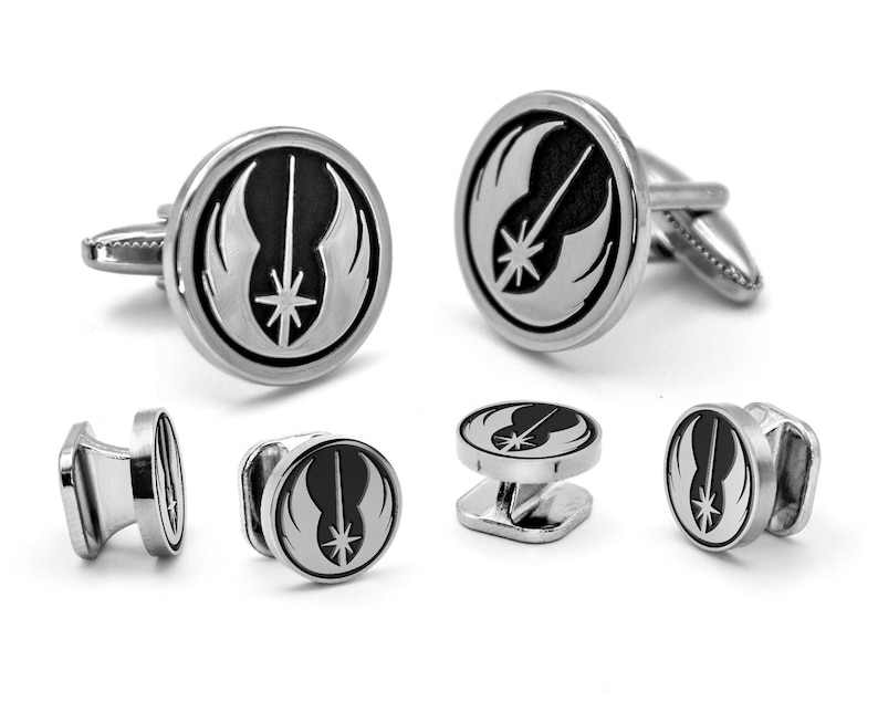 May include: A set of silver cufflinks and collar stays featuring the Rebel Alliance symbol from Star Wars. The symbol is black and white and depicts a lightsaber, a star, and wings.