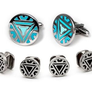 May include: A set of six cufflinks featuring a silver-toned design with a black or blue and white triangular pattern. The cufflinks are circular and have a smooth, polished finish.