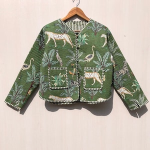 May include: A green quilted jacket with a safari print featuring zebras, leopards, and palm trees. The jacket has a button closure and two patch pockets.