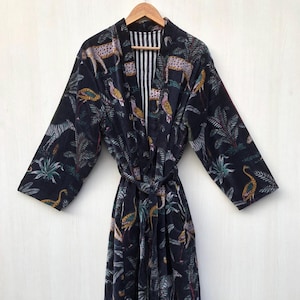 May include: A black velvet robe with a jungle print featuring leopards, zebras, birds, and palm trees. The robe has a tie belt and a striped lining.