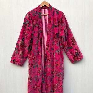 May include: A long pink velvet robe with a floral and bird print. The robe has a white and pink striped lining.