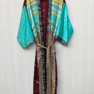 May include: A long, maroon silk robe with a patterned design. The robe has a wide collar and long sleeves. The sleeves are turquoise blue with a yellow and white geometric pattern. The robe is tied at the waist with a matching sash.