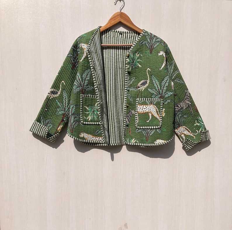 May include: A green quilted jacket with a white striped lining. The jacket features a tropical print with palm trees, zebras, and leopards.