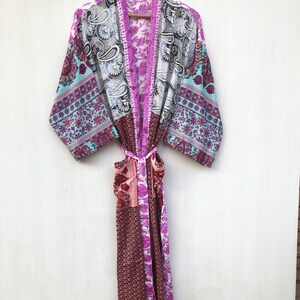 May include: A long, pink and blue patterned silk robe with a sash tie. The robe has a patchwork design with different floral and paisley patterns.