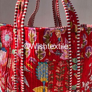 May include: A quilted tote bag featuring a vibrant red base with a multi-coloured floral and botanical print. The bag includes two sturdy handles with a red and white striped pattern. The text @Wishtextile is printed in white across the centre.
