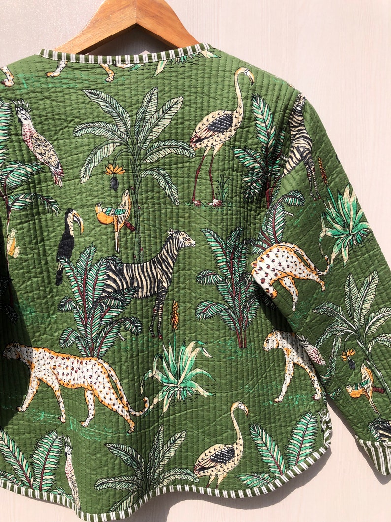 May include: A green quilted jacket with a tropical print featuring zebras, leopards, flamingos, toucans, and palm trees.