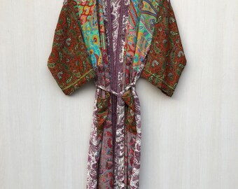May include: A colorful, patterned robe with a paisley design. The robe features a mix of colors including red, green, purple, and blue. It is hanging on a wooden hanger and has a matching belt.