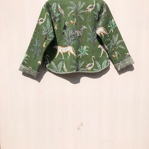 May include: A green quilted jacket with a tropical print featuring zebras, leopards, flamingos, and palm trees.