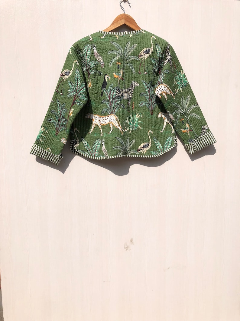 May include: A green quilted jacket with a tropical print featuring zebras, leopards, flamingos, and palm trees.