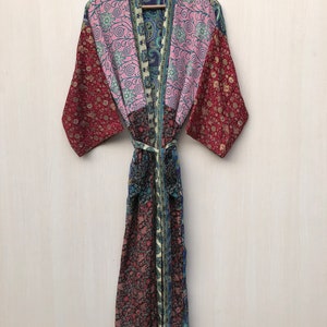 May include: A long, patchwork silk robe with a floral and paisley print in shades of pink, blue, and red. The robe has a tie belt and long sleeves.
