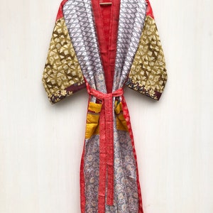 May include: A red, gray, and gold patchwork silk robe with a floral pattern. The robe has a tie belt and long sleeves.