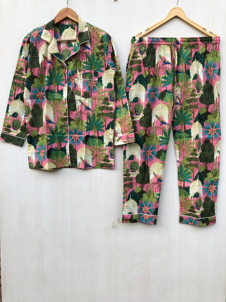 Pu&ograve; includere: Un pigiama rosa e verde con una stampa floreale che presenta pavoni ed edifici. Il set comprende una camicia a maniche lunghe con bottoni e pantaloni abbinati.