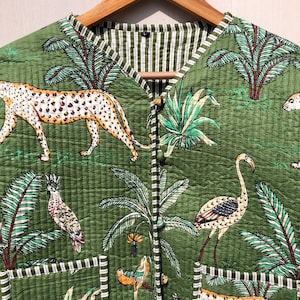 May include: A green quilted vest with a jungle print featuring leopards, flamingos, zebras, and palm trees. The vest has a striped lining and two pockets.