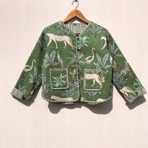May include: A green quilted jacket with a jungle print featuring leopards, zebras, flamingos, and palm trees. The jacket has a button closure and two pockets.