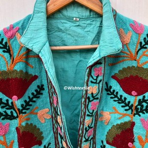 May include: A turquoise blue embroidered jacket with a floral design. The jacket has a collar and a button closure. The size tag says "XL".