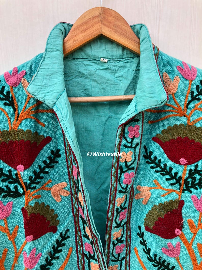May include: A turquoise blue embroidered jacket with a floral design. The jacket has a collar and a button closure. The size tag says "XL".