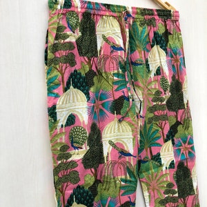 Pu&ograve; includere: Pantaloni rosa con una stampa colorata di pavoni, alberi ed edifici. I pantaloni hanno una cintura elastica e un cordoncino.