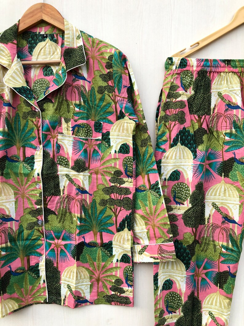 Pu&ograve; includere: Un pigiama rosa e verde con una stampa di pavoni, alberi ed edifici. Il set comprende una camicia a maniche lunghe e pantaloni.