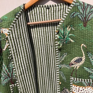 May include: A green quilted jacket with a striped lining. The jacket features a button closure and a print of tropical plants, birds, and animals.