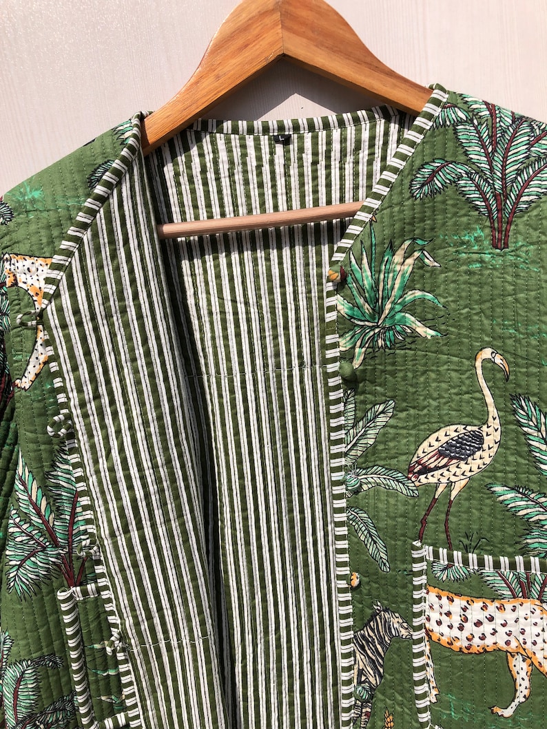 May include: A green quilted jacket with a striped lining. The jacket features a button closure and a print of tropical plants, birds, and animals.