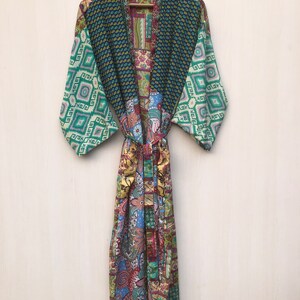 May include: A long, green, blue, and pink patterned silk robe with a sash tie. The robe has a patchwork design with various floral and geometric patterns.