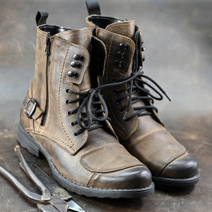May include: A pair of brown leather motorcycle boots with black laces and a zipper on the side. The boots have a rugged look and are made of high-quality leather.