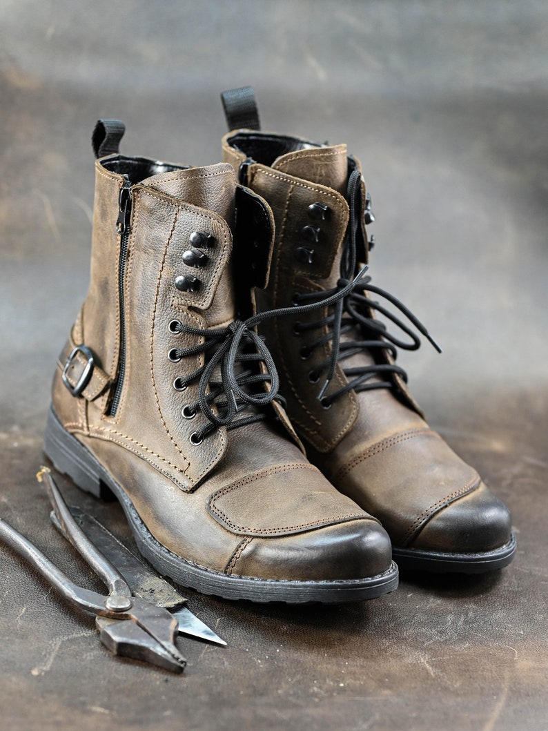 May include: A pair of brown leather motorcycle boots with black laces and a zipper on the side. The boots have a rugged look and are made of high-quality leather.