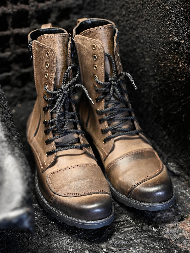 May include: A pair of brown leather boots with black laces. The boots have a round toe and a thick sole.