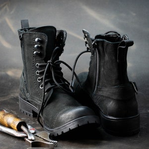K&ouml;nnte beinhalten: Zwei schwarze Lederstiefel mit Schn&uuml;rsenkeln und Rei&szlig;verschl&uuml;ssen. Die Stiefel haben einen robusten Look und sind aus strapazierf&auml;higem Material gefertigt.