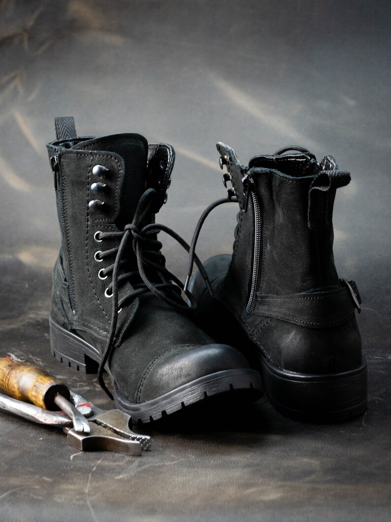 K&ouml;nnte beinhalten: Zwei schwarze Lederstiefel mit Schn&uuml;rsenkeln und Rei&szlig;verschl&uuml;ssen. Die Stiefel haben einen robusten Look und sind aus strapazierf&auml;higem Material gefertigt.